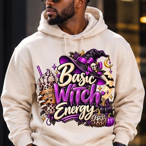May include: A beige hooded sweatshirt featuring a graphic print of a purple witch hat, a leopard print cup labeled Witch Fuel held by a skeleton hand, and pumpkins. The text reads Basic Witch Energy in purple and cream stylized lettering.