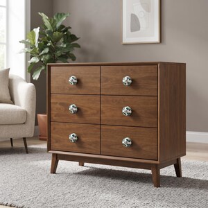 Puede incluir: Una cómoda de madera marrón con seis cajones, cada uno con un pomo redondo de cerámica blanca decorado con un patrón floral azul y verde. La cómoda se apoya sobre cuatro patas cónicas y tiene un marco rectangular liso con veta de madera visible.