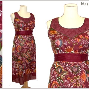 Könnte beinhalten: Ein maronfarbenes Maxikleid mit Blumendruck und einem dunkelbraunen Besatz am Ausschnitt. Das Kleid hat ein tailliertes Oberteil und einen fließenden Rock.