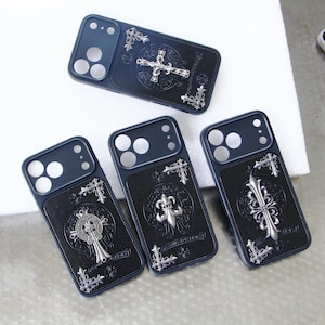 Puede incluir: Cuatro fundas negras para smartphone con adornos de metal plateado. Cada funda muestra intrincados motivos de cruces y flores de lis, con detalles decorativos en las esquinas y patrones circulares grabados en la parte posterior.