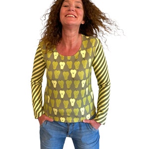 May include: A long-sleeved shirt with a green pear print and yellow and green striped sleeves. The shirt has a scoop neck.