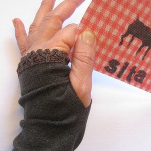 Puede incluir: Un par de guantes sin dedos marrones con un borde de encaje. Los guantes están hechos de un tejido suave y elástico, perfectos para mantener las manos calientes y permitir el uso de los dedos.