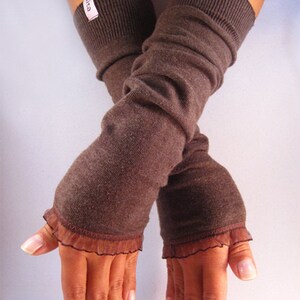 Puede incluir: Un par de calentadores de brazos marrones con un borde de encaje. Los calentadores de brazos están hechos de un tejido suave y de punto.