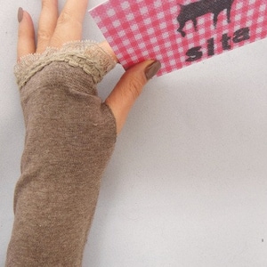 Puede incluir: Un guante sin dedos marrón con un borde de encaje. El guante se lleva en una mano que sostiene una tarjeta a cuadros rojos y blancos con una silueta negra de un reno y la palabra "Sita" impresa en ella.