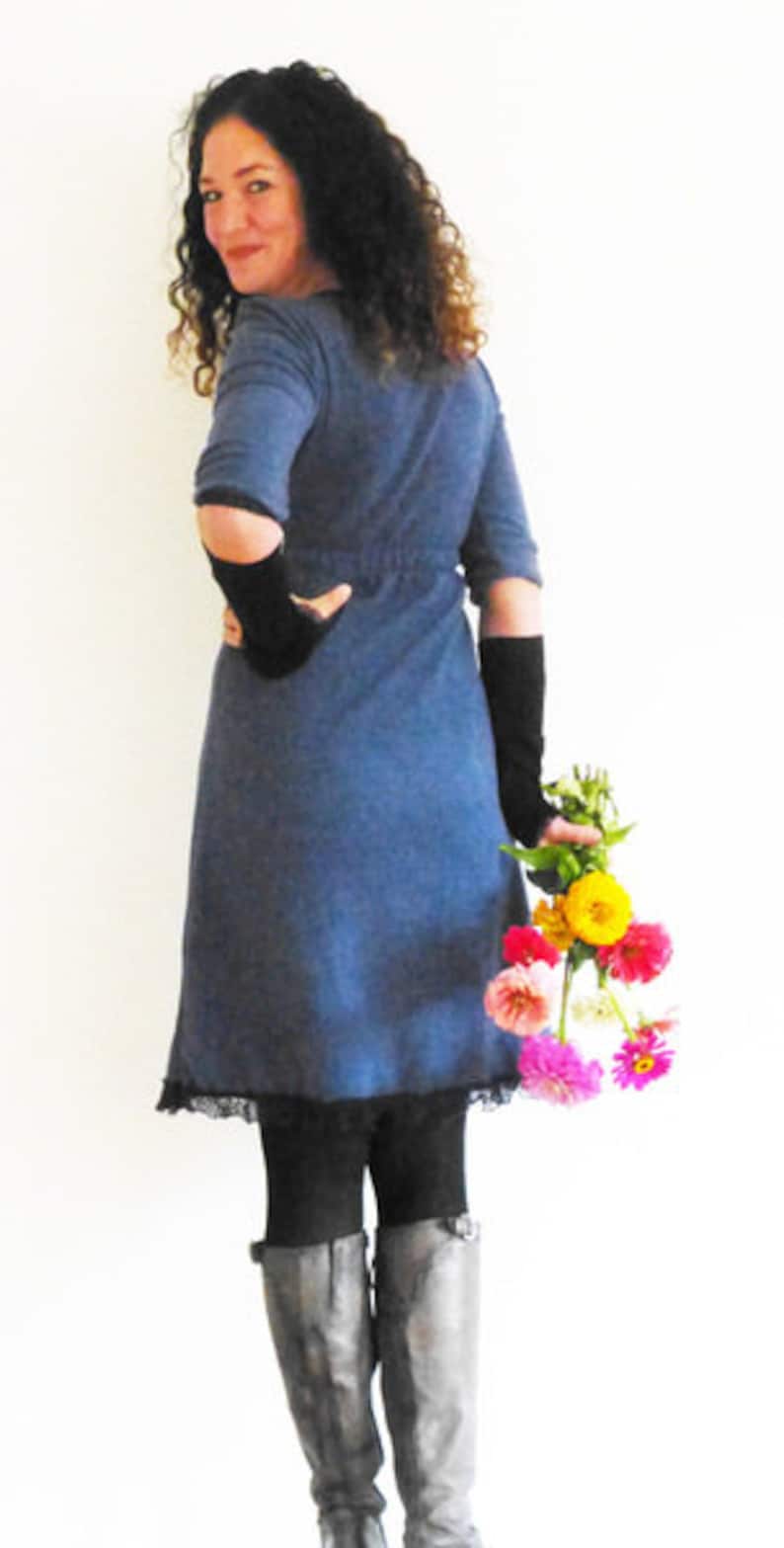 May include: A woman wearing a blue denim dress with black lace trim and black gloves, holding a bouquet of pink, yellow, and orange flowers.