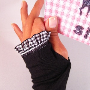 Puede incluir: Guantes negros sin dedos con un volante a cuadros blanco y negro en la muñeca.