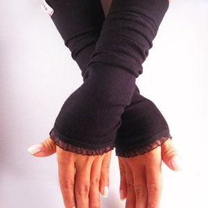May include: A pair of black fingerless gloves with lace trim. The gloves are made of a soft, stretchy fabric and extend to the elbow.