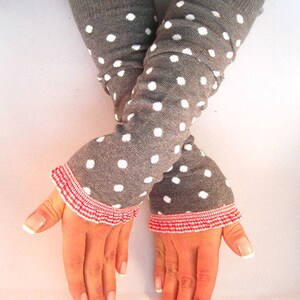 Puede incluir: Calentadores de brazo grises con lunares blancos y ribete de volantes rojos y blancos. Estos accesorios están diseñados para mantener los brazos calientes y añadir un toque de estilo. Los calentadores están hechos de un material de punto suave.