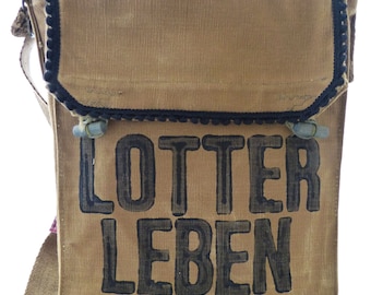 Może przedstawiać: Brązowa torba na ramię z płótna z czarną lamówką i nadrukiem "LOTTER LEBEN" w kolorze czarnym.