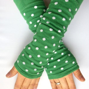 Può includere: Un paio di scaldamani verdi con pois bianchi. Gli scaldamani sono realizzati in un tessuto morbido ed elastico, perfetti per mantenere le braccia al caldo nei mesi più freddi.