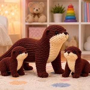 May include: Three crocheted otter plush toys in varying sizes, each featuring dark brown yarn bodies with cream-colored chest and face patches, small black bead eyes, and textured stitching, arranged together on a patterned rug.