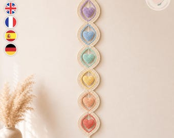 May include: A vertical crochet wall hanging featuring six interconnected cream-colored almond-shaped frames. Each frame contains a small, stuffed heart in a different pastel color: lavender, light blue, mint green, yellow, peach, and coral.