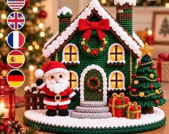 May include: A crochet Christmas scene featuring a green house with white snow-covered roof, a red bow, and a wreath. A Santa Claus figure stands in front, next to a decorated Christmas tree and two wrapped gifts on a circular white base.