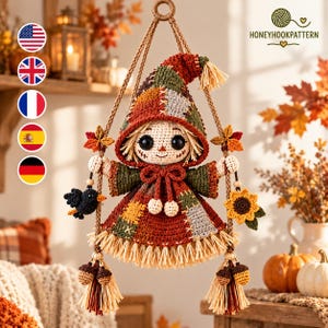 May include: A crocheted scarecrow doll hanging from a rope, featuring a patchwork hood and dress in autumn colours of rust, olive, and tan. The doll has black button eyes, a stitched mouth, and straw-like hair, accented with a black bird and sunflower.