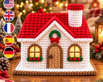 May include: A crocheted house with a white textured exterior, a red roof, and a white chimney. The front features a brown door, two windows with red flower boxes, and a green wreath with a red bow. The text HoneyHookPattern is visible.