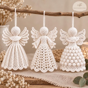 May include: Three off-white crochet angel ornaments hanging from a wooden branch. Each angel features a round head, spread wings, and a unique skirt design: one with vertical ribs, one with an open lattice pattern, and one with bobble stitches.