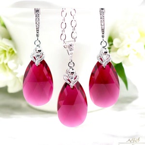 Peut inclure: Un ensemble de bijoux composé d'un pendentif en forme de larme et de boucles d'oreilles avec une chaîne en argent et des accents de cristal rouge.