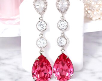 Peut inclure: Une paire de longues boucles d'oreilles pendantes argentées avec des cristaux en forme de goutte rose et des cristaux ronds transparents.