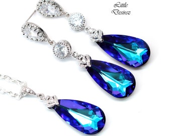 May include: A silver necklace and earrings set with teardrop-shaped blue iridescent crystals and clear rhinestones.