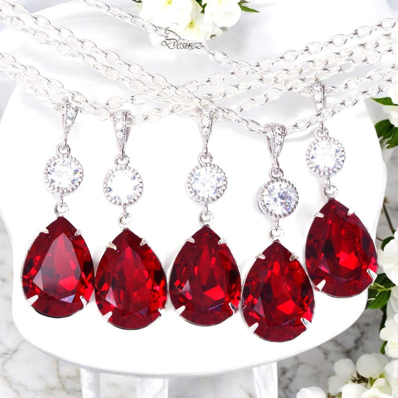 May include: Five silver necklaces with red teardrop-shaped crystal pendants and smaller clear crystal accents.