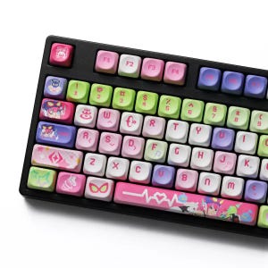 Puede incluir: Un teclado mecánico negro con un conjunto de teclas personalizadas en una paleta de colores pastel rosa, verde claro, morado y blanco. Las teclas muestran varios iconos gráficos, símbolos e ilustraciones de estilo anime en la barra.