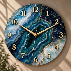 Può includere: Un orologio da parete rotondo con un motivo in pietra d'agata blu e verde acqua con venature dorate. Il quadrante mostra numeri arabi dorati da 1 a 12 e tre sottili lancette color oro posizionate al centro dell'orologio.