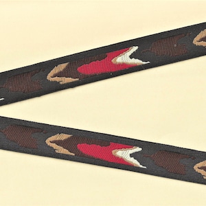 May include: Black, red, brown, and white camouflage patterned ribbon. The ribbon has a woven design.
