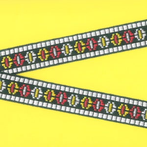 Op de afbeelding: Een groen, wit, rood en geel gestreept lint met een geometrisch ontwerp. Het lint ligt op een gele achtergrond.