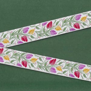 Cinta jacquard FLORAL E-75-A de poliéster con ribete de 24 mm de ancho. Fabricada en Francia. Color blanco con tulipanes rojos, morados y amarillos, tallos y hojas verdes.