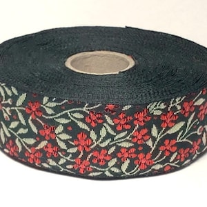 May include: A roll of black and green ribbon with a red floral pattern. The ribbon is wound around a cardboard core.