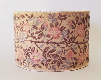 Puede incluir: Pantalla de lámpara cilíndrica con un diseño floral de rosas rosas, tallos marrones y hojas gris azuladas sobre un fondo beige. La pantalla tiene un ribete decorativo en los bordes superior e inferior. El diseño recuerda a ilustraciones botánicas vintage.