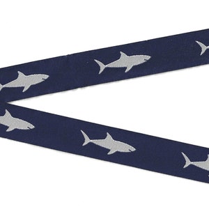 Op de afbeelding: Een marineblauw lint met een herhalend patroon van witte haaien silhouetten.