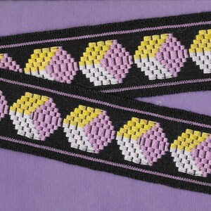 May include: Black and white trim with a repeating pattern of pink, yellow, and white circles. The trim is woven with a textured surface.