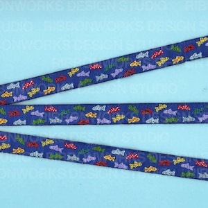 May include: Navy blue ribbon with a repeating pattern of colorful fish. The fish are in shades of red, yellow, green, and purple. The ribbon is likely used for crafting or gift wrapping.