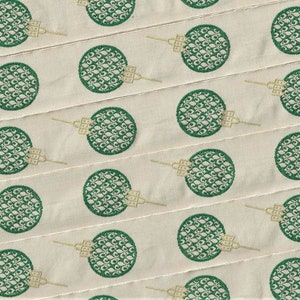 Puede incluir: Una cinta de tela blanca con un patr&oacute;n repetido de c&iacute;rculos verdes. Cada c&iacute;rculo tiene un dise&ntilde;o detallado de un patr&oacute;n floral estilizado.