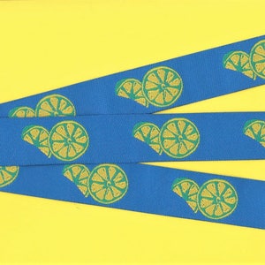 Może przedstawiać: Trzy niebieskie wstążki z powtarzającym się wzorem żółtych plastrów cytryny na żółtym tle.