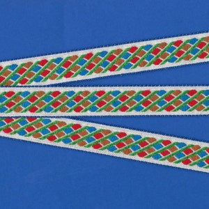 May include: Three white ribbons with a repeating pattern of red, blue, green, and brown squares. The ribbons are woven with a diagonal pattern.