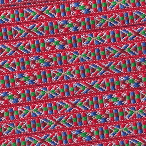 May include: Red fabric with a repeating pattern of blue, green, and white geometric shapes.