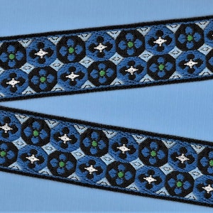 May include: Black, blue, white, and green patterned trim with a geometric design. The trim is woven and has a repeating pattern.