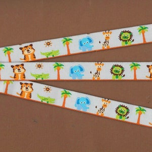 May include: White ribbon with a repeating pattern of orange tigers, blue elephants, green lions, green palm trees, green crocodiles, and yellow suns. The ribbon has an orange border.