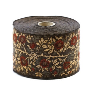 May include: A roll of decorative ribbon featuring a floral pattern. The ribbon has a dark brown background with a repeating design of red flowers and tan leaves and vines. The ribbon is likely used for crafts, gift wrapping, or other decorative purposes.