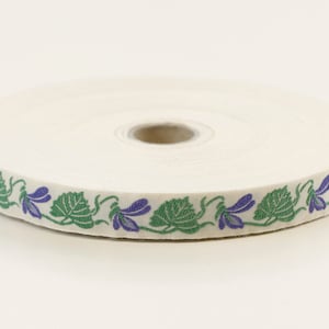 Cinta jacquard KAFKA C-01/02 de algodón orgánico tejido, 16 mm de ancho, fondo marfil con violetas moradas y hojas/enredaderas verdes.