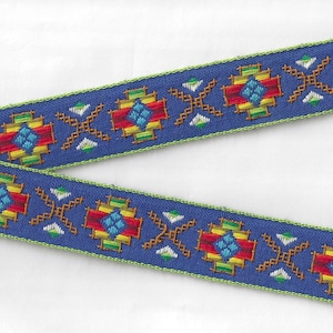 May include: Two strips of blue woven ribbon with a geometric pattern. The pattern features red, yellow, green, and blue diamond shapes, and brown and white cross-like designs. The edges are trimmed with green stitching.