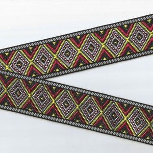 Peut inclure: Garniture noire et blanche avec un motif géométrique de diamants rouges, jaunes et argentés. La garniture a une texture tissée.