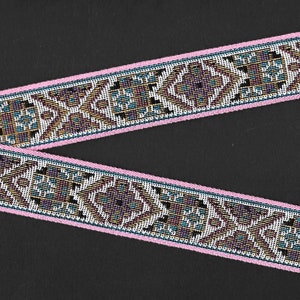 May include: Pink trim ribbon with a white background and a geometric pattern in shades of brown, blue, and gold.