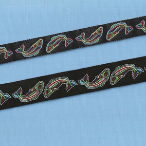 May include: Black ribbon with a repeating pattern of colorful fish. The fish are outlined in black and have a variety of colors, including red, green, blue, and yellow.