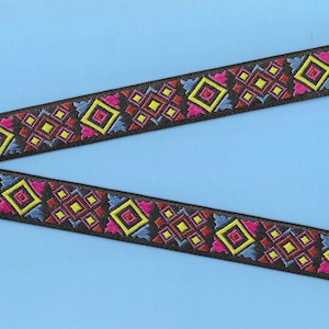 May include: Black ribbon with a colorful geometric pattern of red, yellow, blue, and pink squares. The ribbon is on a light blue background.