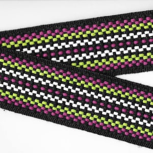 Op de afbeelding: Zwart geweven lint met een herhalend patroon van witte, groene en roze vierkanten en stippen.