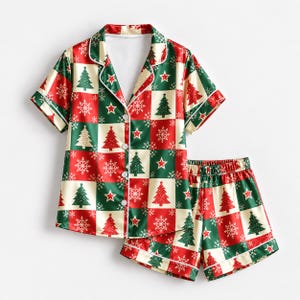 May include: A short-sleeve button-down pajama shirt and matching shorts set featuring a checkered pattern of red, green, and cream squares. The design includes repeating graphics of Christmas trees, white snowflakes, and red stars throughout.