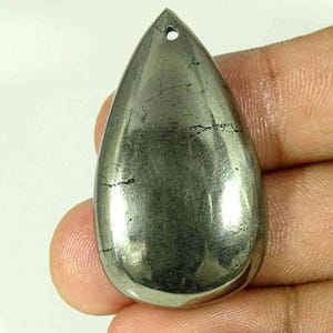 May include: A polished, teardrop-shaped pyrite pendant with a metallic, brassy-gold lustre and a smooth, reflective surface. The stone features a small, circular hole drilled near the top point for suspension, showcasing natural dark surface inclusions.